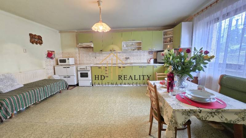 Kuchyňa v rodinnom dome so zelenou linkou, jedálenským stolom a dekoráciou.