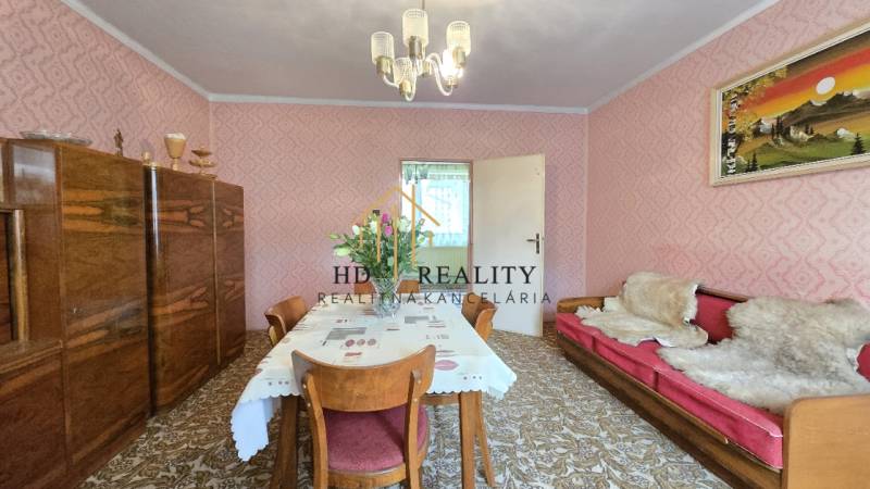 Jedáleň v rodinnom dome s květinovým obrusom, drevo a ružové steny.