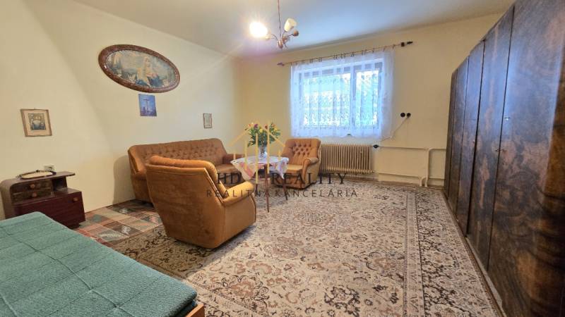 Obývacia izba v rodinnom dome s béžovým nábytkom a veľkým kobercom.