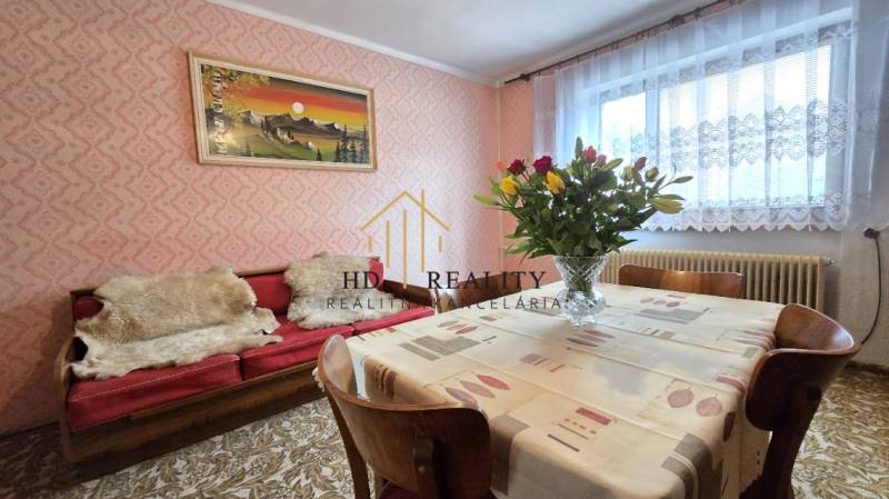 Jedáleň v rodinnom dome, so stoličkami, stolom, kvetmi a obrazom na stene.