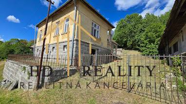 Rodinný dom v Chrťanoch s kamenným plotom a zeleňou na pozadí.