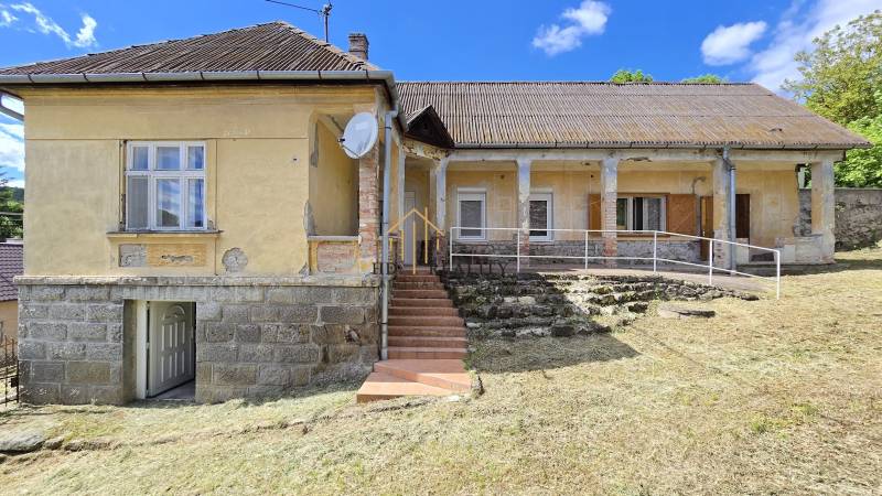 Rodinný dom v Chrťanoch s kamenným múrom a schodiskom na trávnatom pozemku.